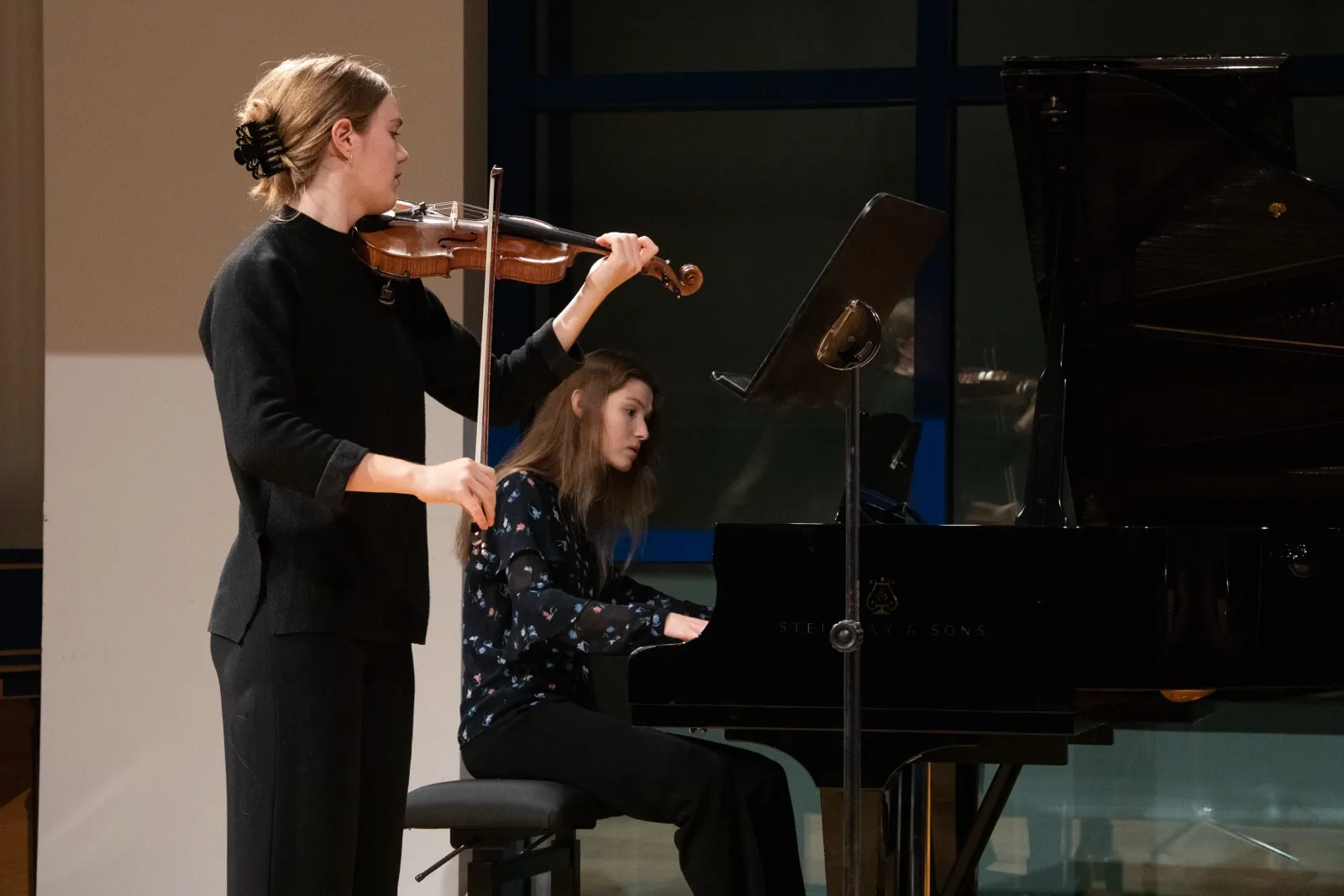 Annika Spegg spielt im Stehen Geige neben einer Pianistin am Steinway-Flügel im Saal der HMDK Stuttgart.