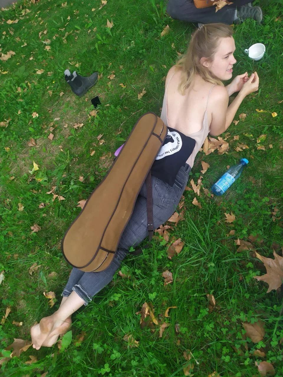 Annika Spegg liegt mit Geigenkasten auf einer herbstlichen Wiese.