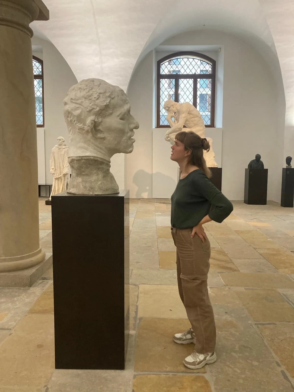 Annika Spegg im Skulpturensaal, im Profil vor einer Büste auf schwarzem Sockel.